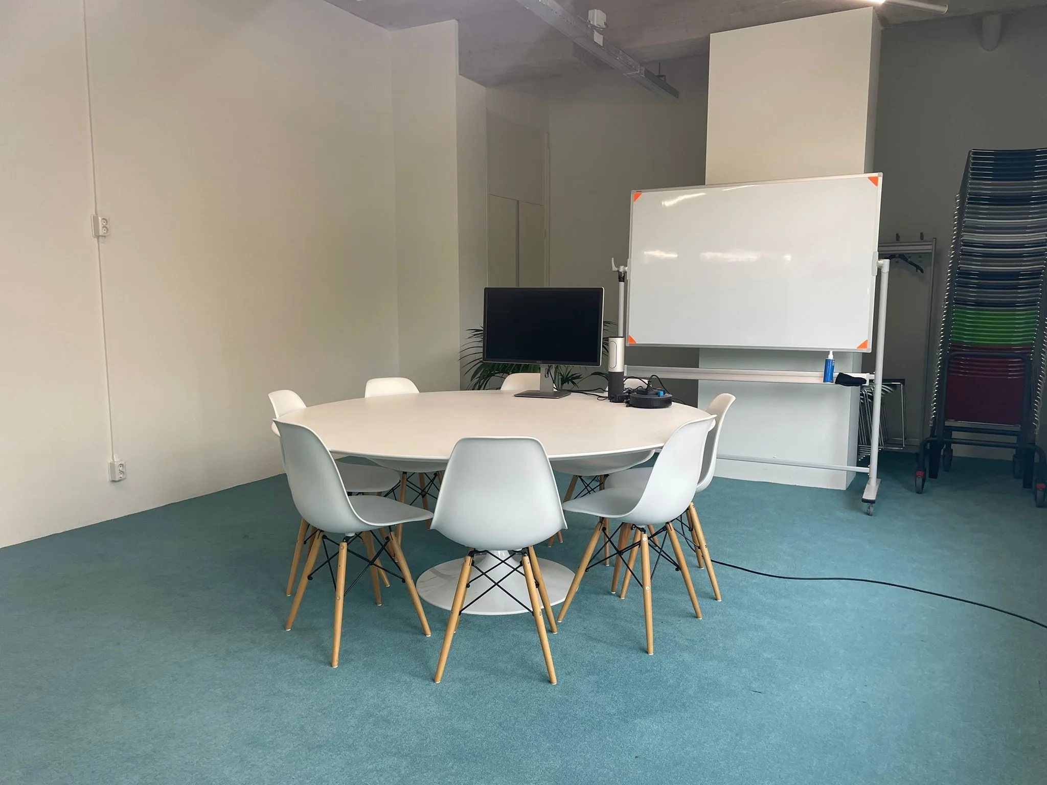 Vergaderruimte aan de Van Leijenberghlaan met ronde tafel, witte stoelen, monitor en verrijdbaar whiteboard.